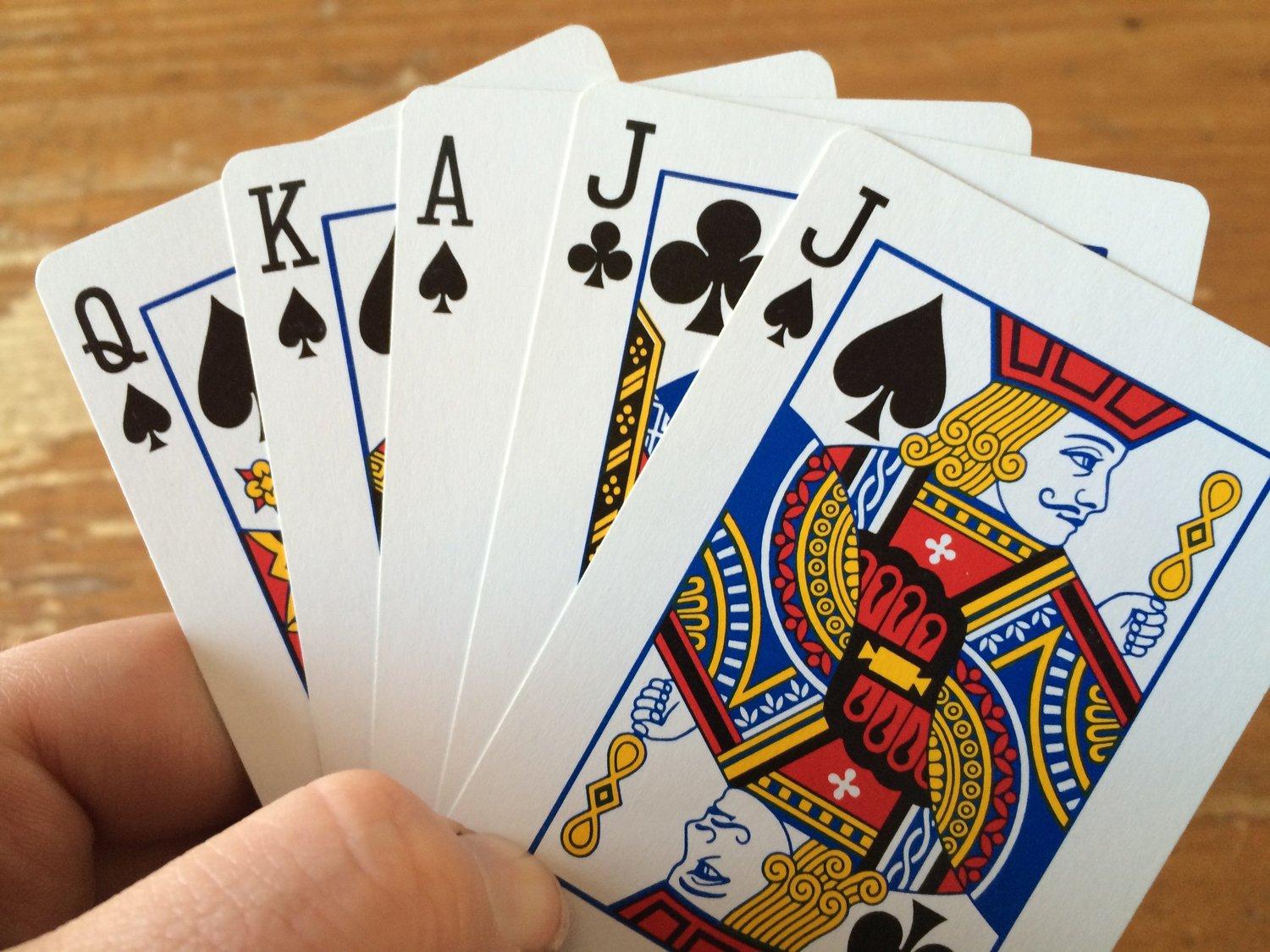 A hand holding a royal flush in spades and clubs.